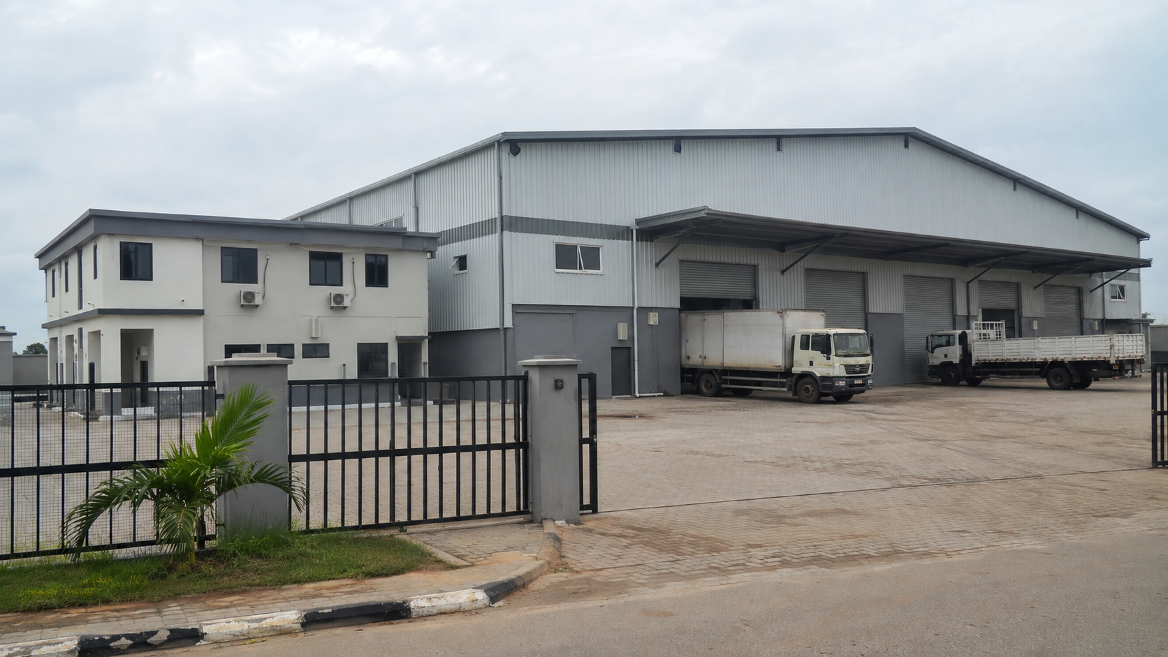Completed steel-clad warehouse with loading doors, delivery trucks and office wing