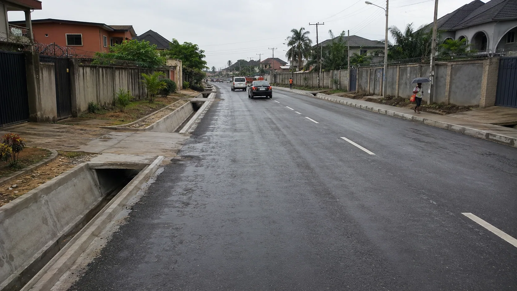 Completed asphalt road with line marking, concrete drains and culvert crossings