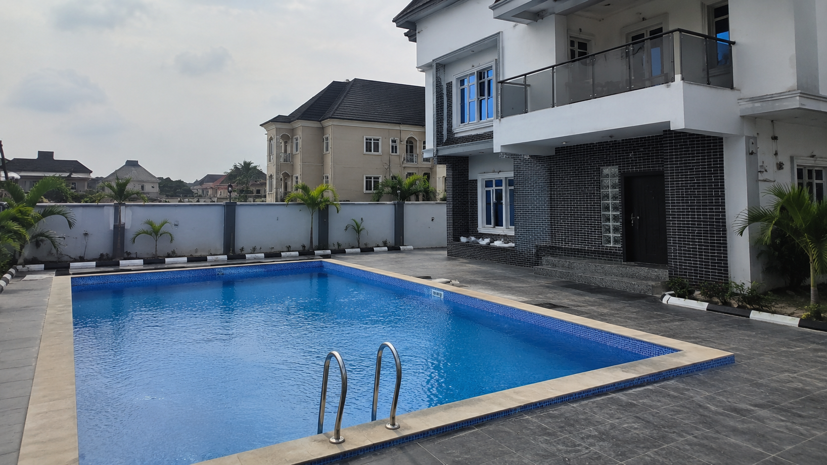 Completed rectangular swimming pool with tiled deck and landscaped setting